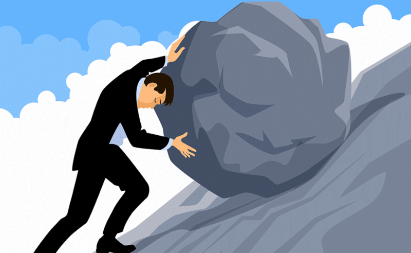 Businessman pushing a boulder up a cliff