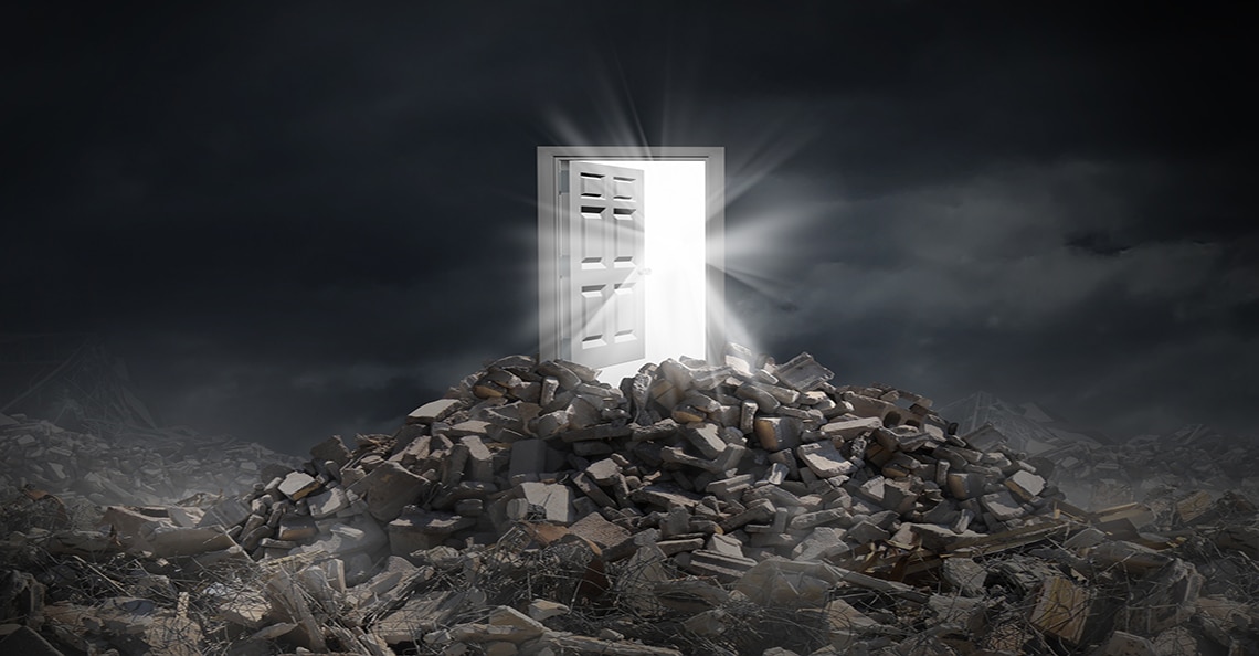 a door on top of rubble showing light at the end of the tunnel